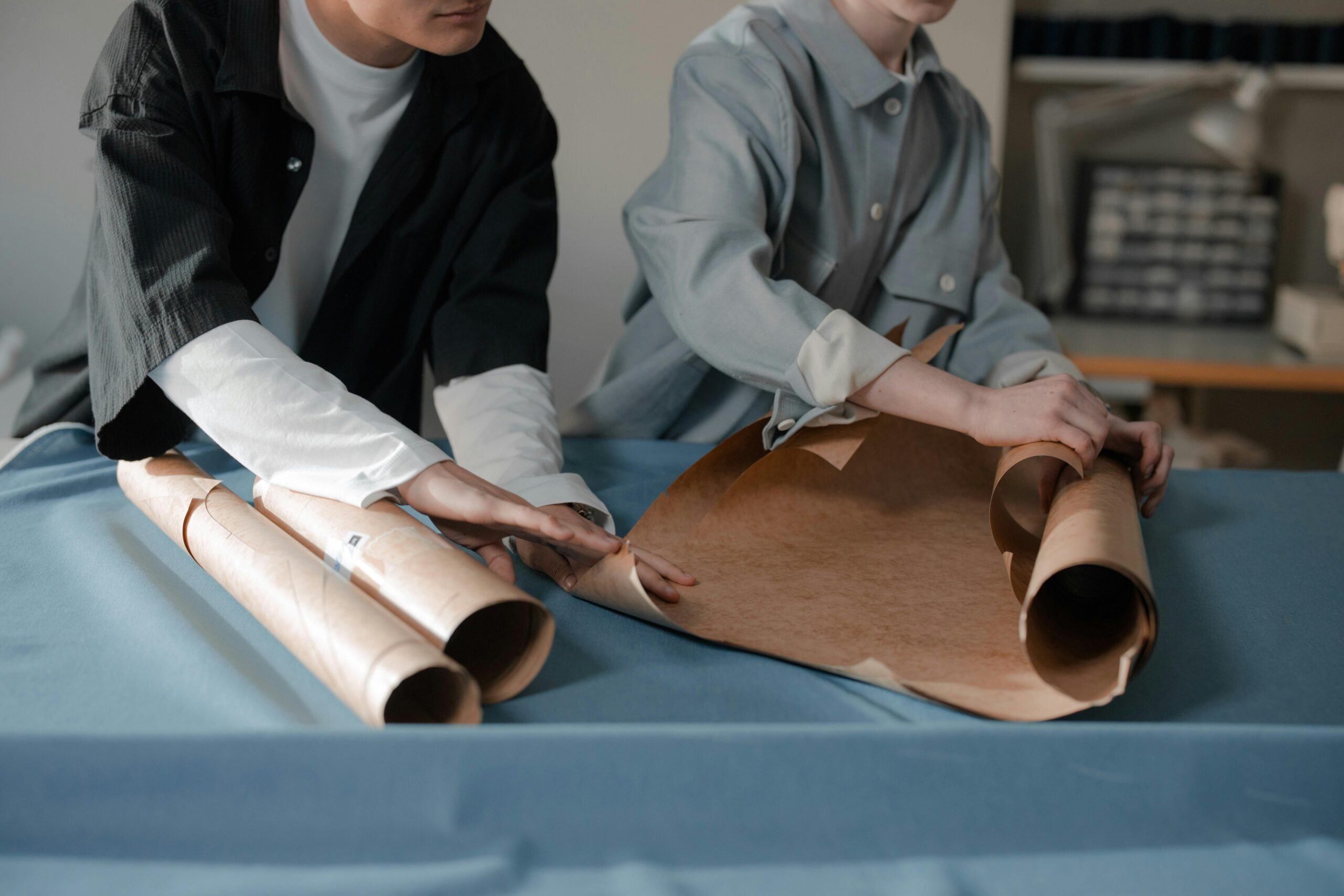 Two designers collaborate on pattern cutting in a fashion studio, highlighting teamwork.