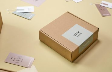 Elegant cardboard packaging with clothing labels and tags displayed on a light surface.